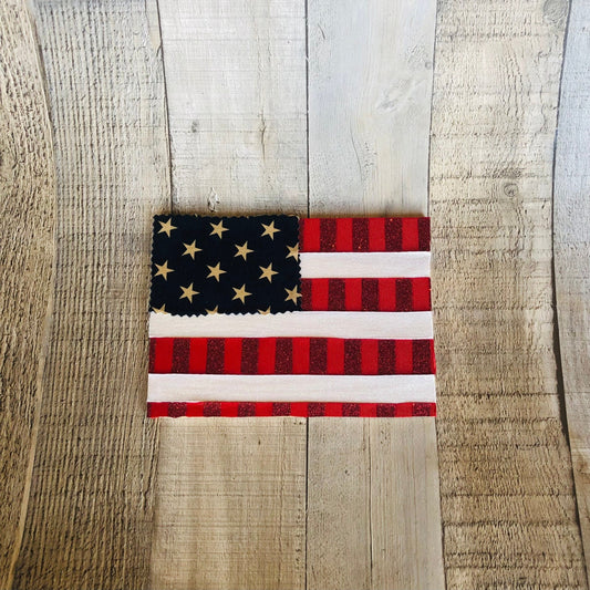This is an American flag craft made with fabric and ribbon on a wood plaque. The craft kit is available on seniorlycreations.com.