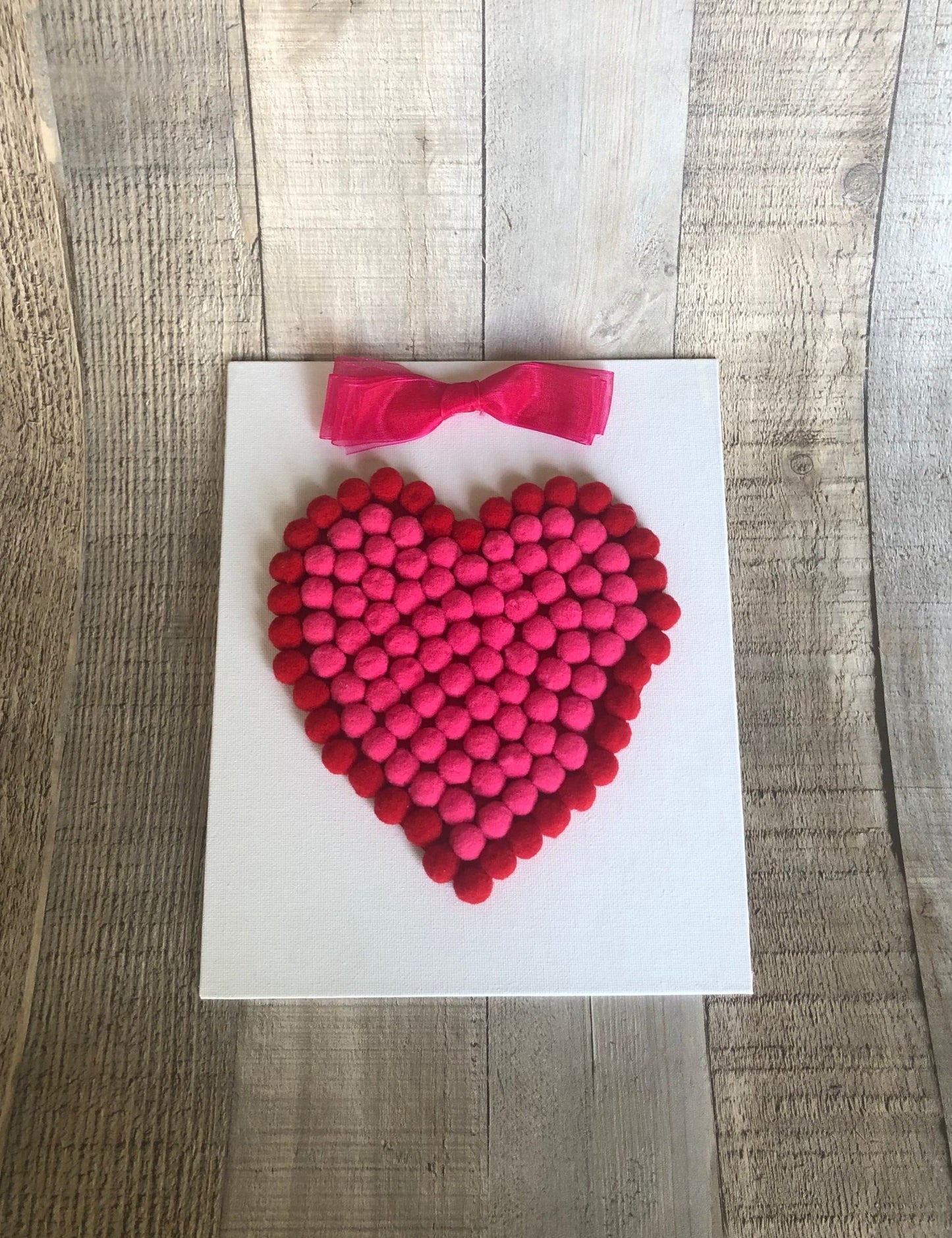 This is a Valentine's heart craft made with mini pom poms in red and hot pink. The craft kit is available on seniorlycreations.com.