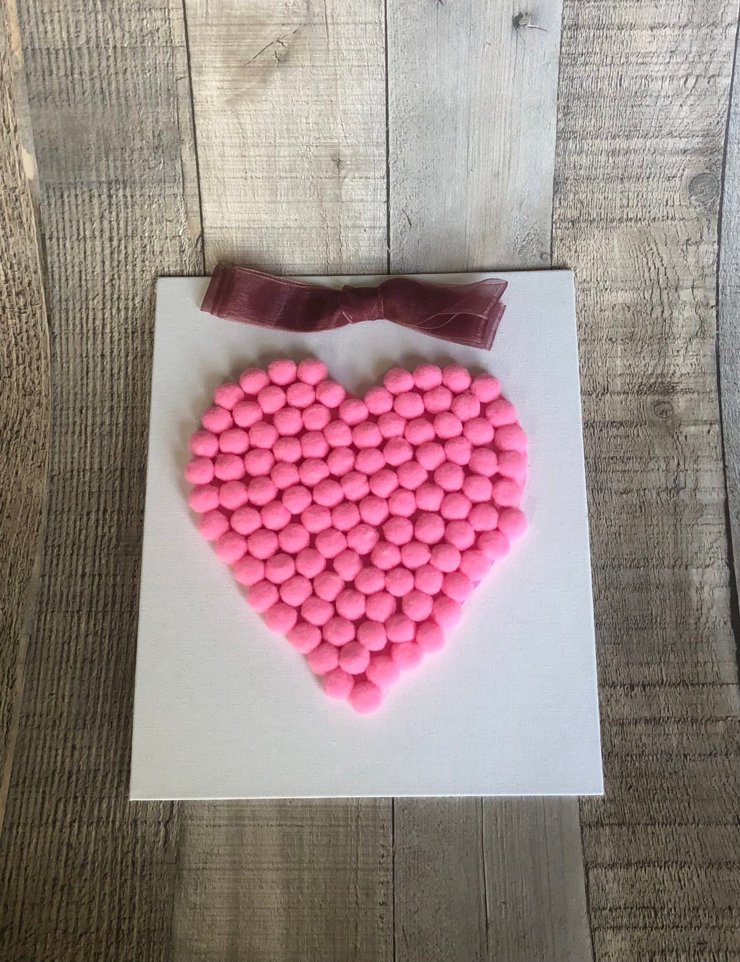 This is a Valentine's heart craft made with mini pom poms in pink. The craft kit is available on seniorlycreations.com.